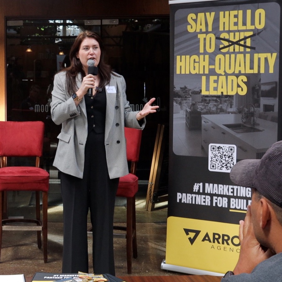 Emily Williams speaking with a microphone in front of an Arrow Agency banner